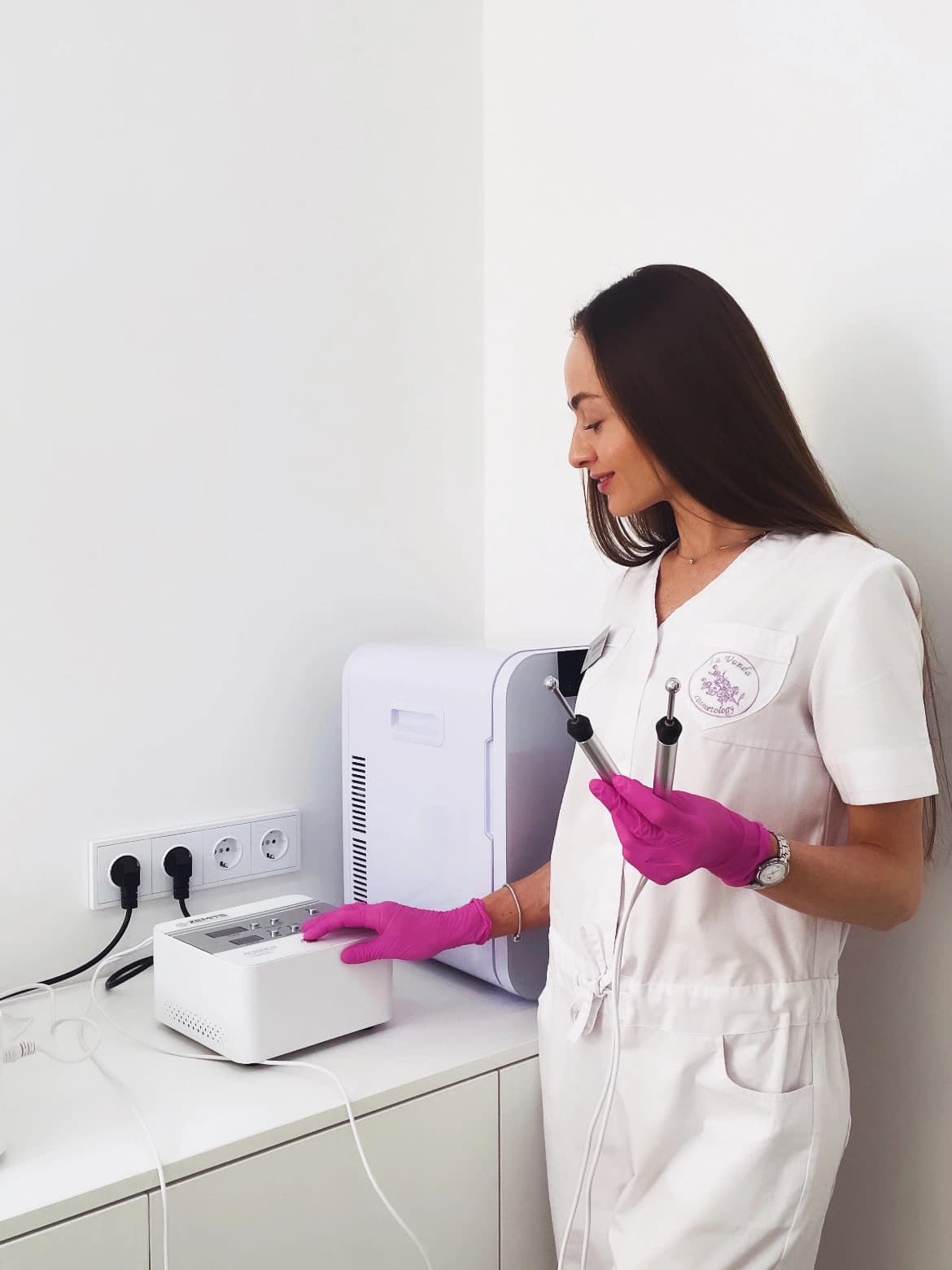 Cosmetologist in a white uniform preparing a skin care device before a treatment